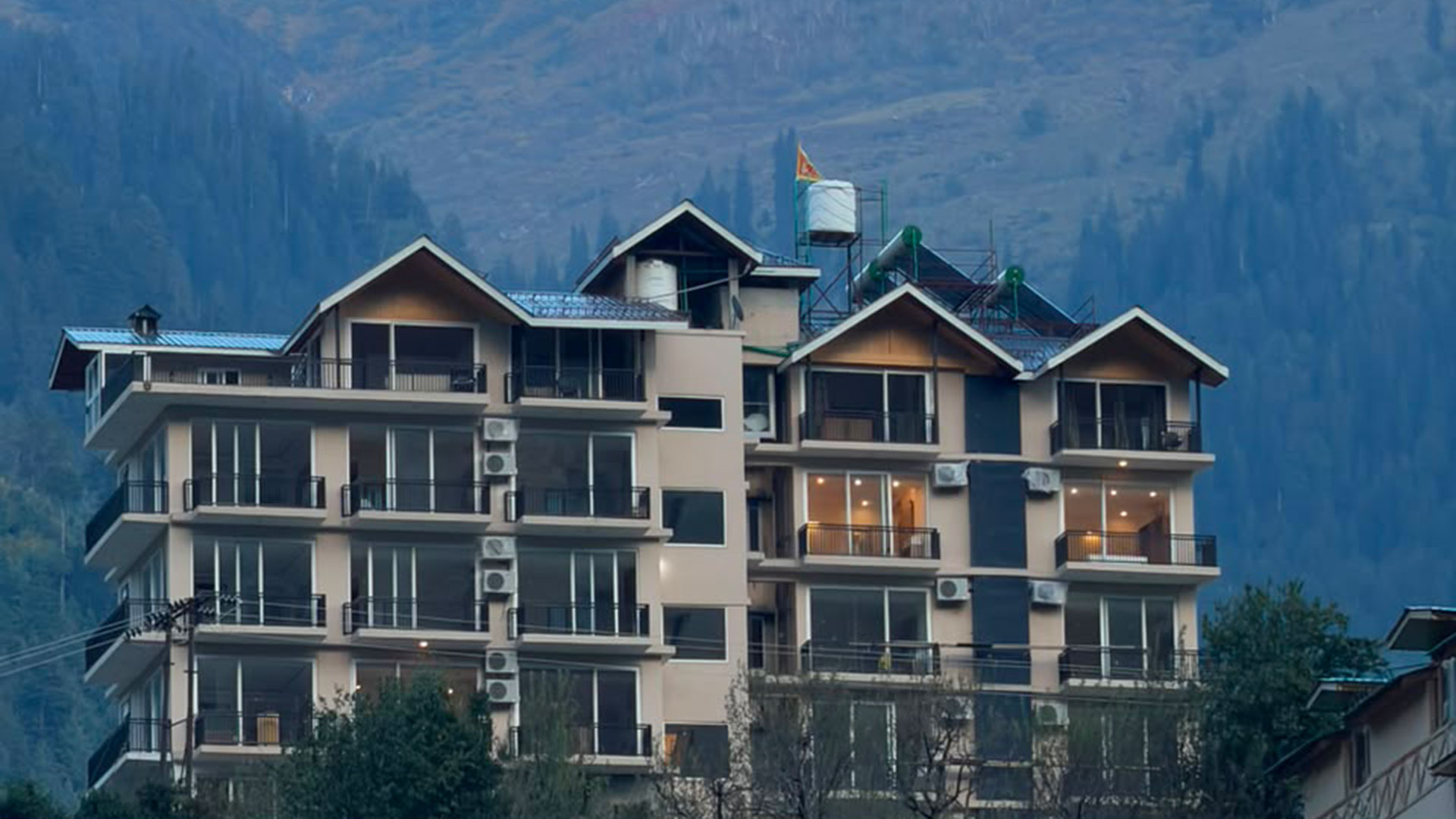 Hotel Namami, a hillside hotel in Manali with forested Himalayan slopes behind it.